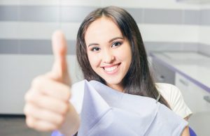 A Woman in a dental chair with her thumb up
